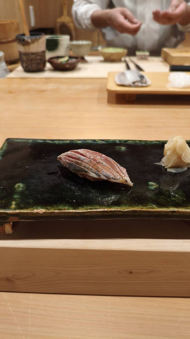 寿司店のカウンターに出された握りと、奥で握っている職人の手元