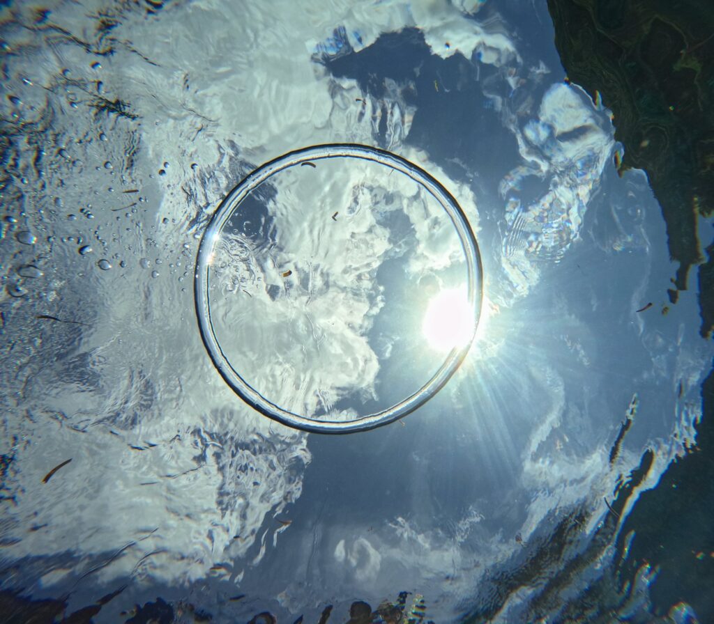 沖縄で初めてのダイビング中に水中から見上げた太陽とバブルリング