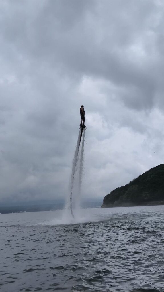 フライボードの見本で沖を高く飛んでいるところ